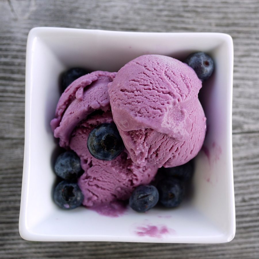 Two scoops of blueberry ice cream with fresh blueberries