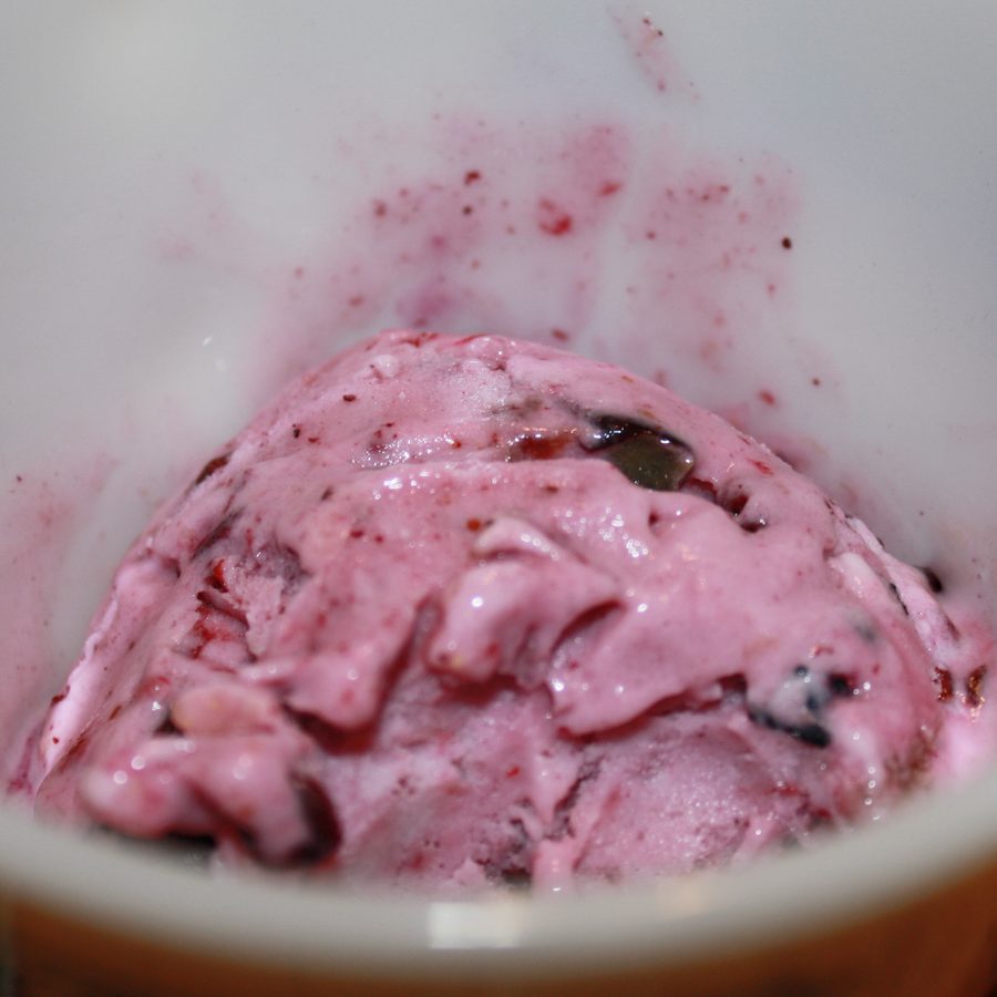 A tub of berry ice cream with whole berries through it