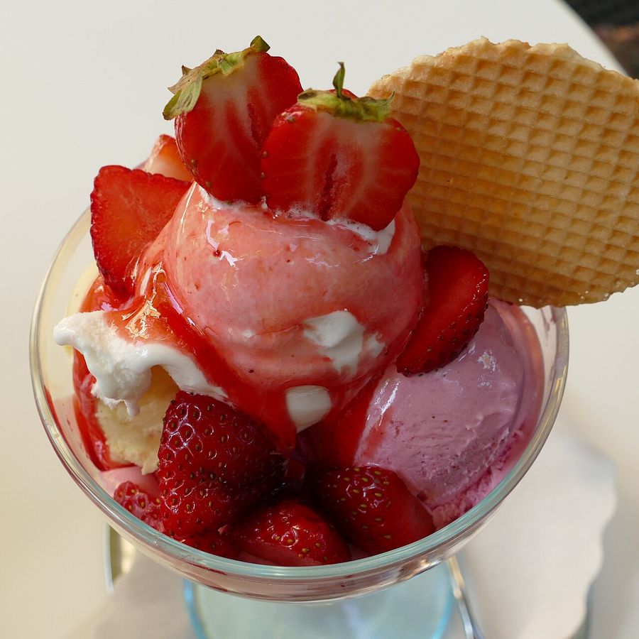 Strawberry ice cream topped with fresh strawberries and a wafer